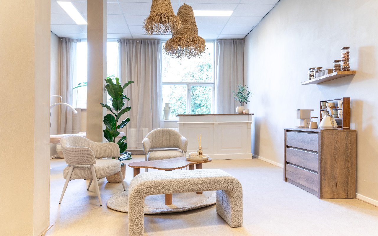 De salon van Femmora Clinic met rieten hanglampen, zithoek en balie