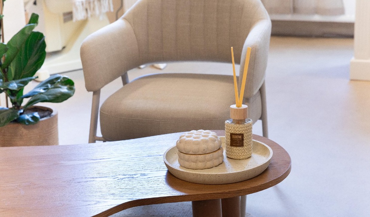 Fauteuil en houten tafel met geurstokjes en een plant in de wachtruimte